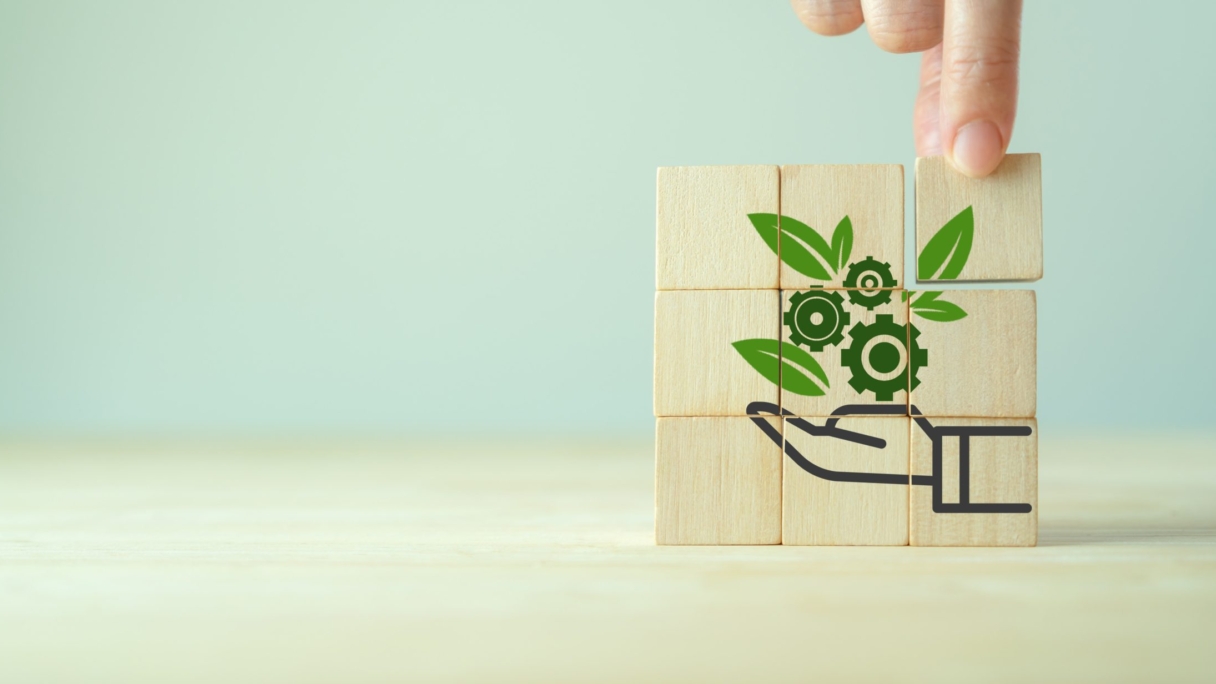 A hand placing a piece of wood with a drawing of a hand and leaves